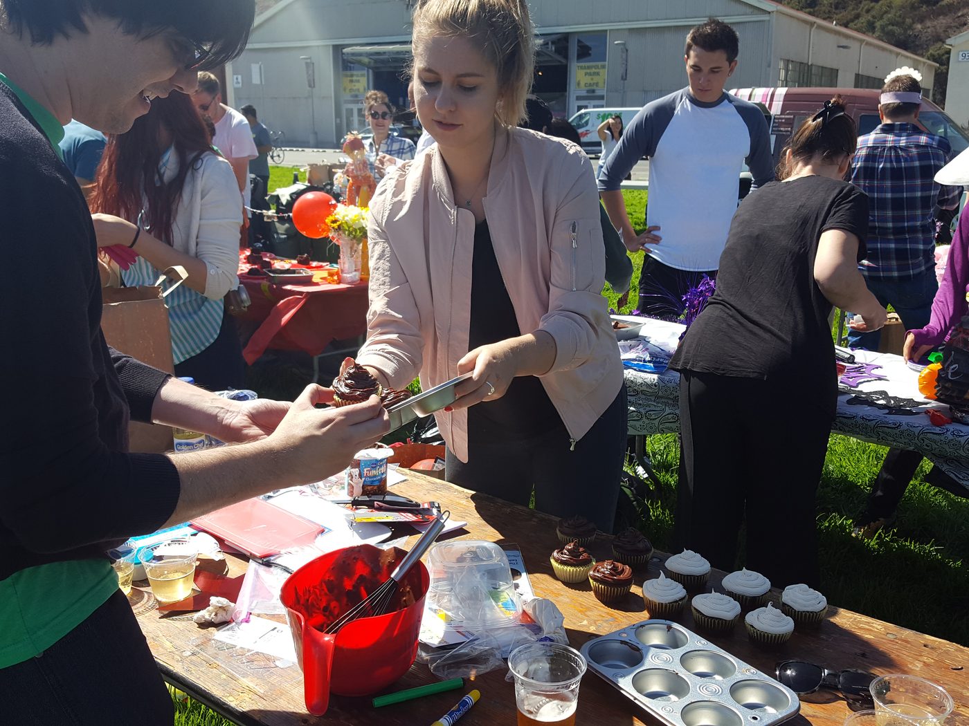Teammates concentrating on a crowded outdoor dessert decorating table
