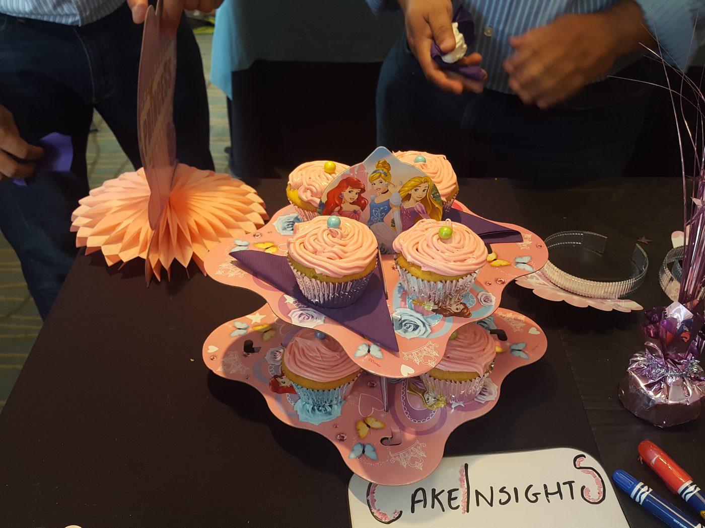 An elaborate pink cupcake display with flowers and butterfly decorations